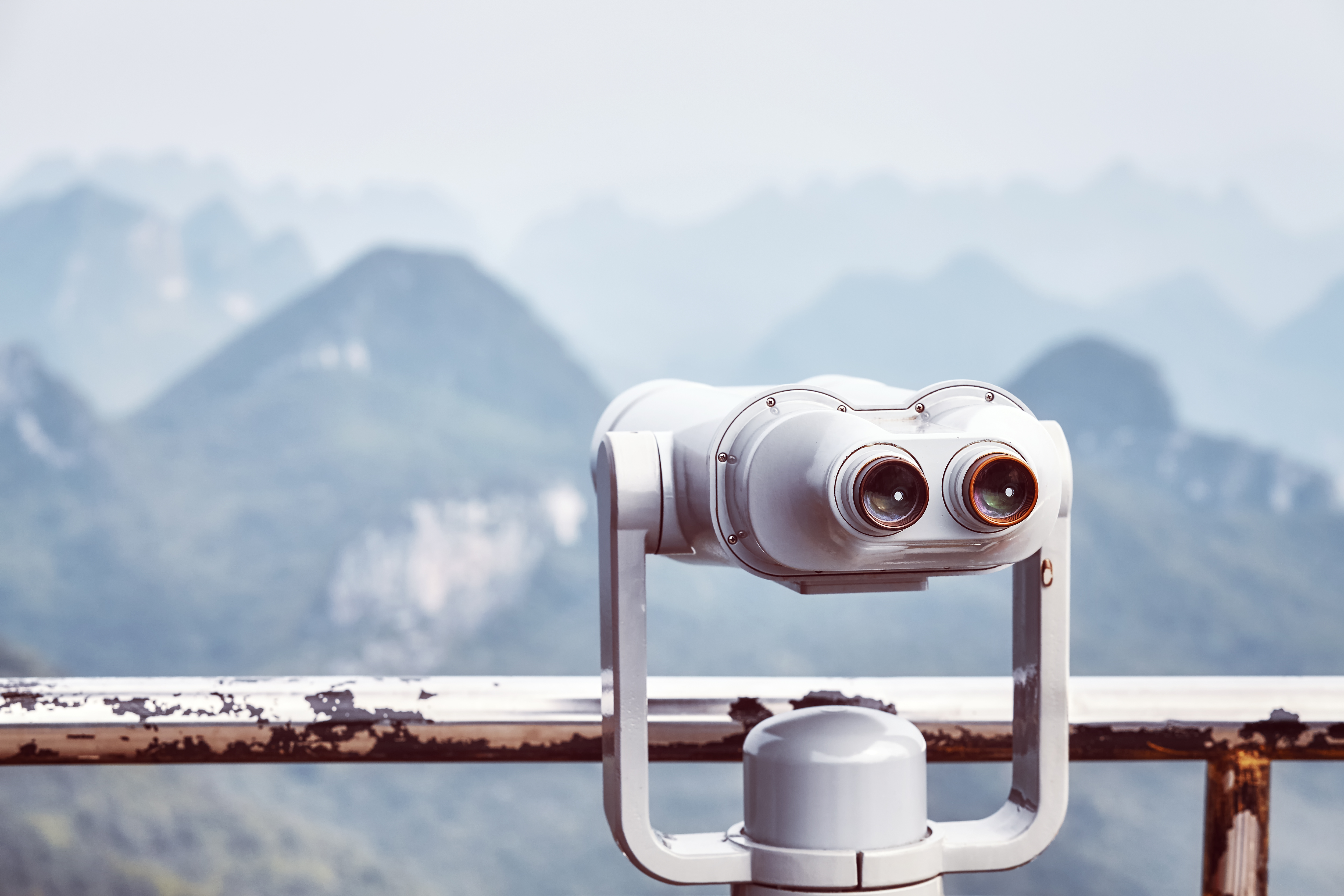 Vintage toned picture of tourist binoculars pointing at mountains.